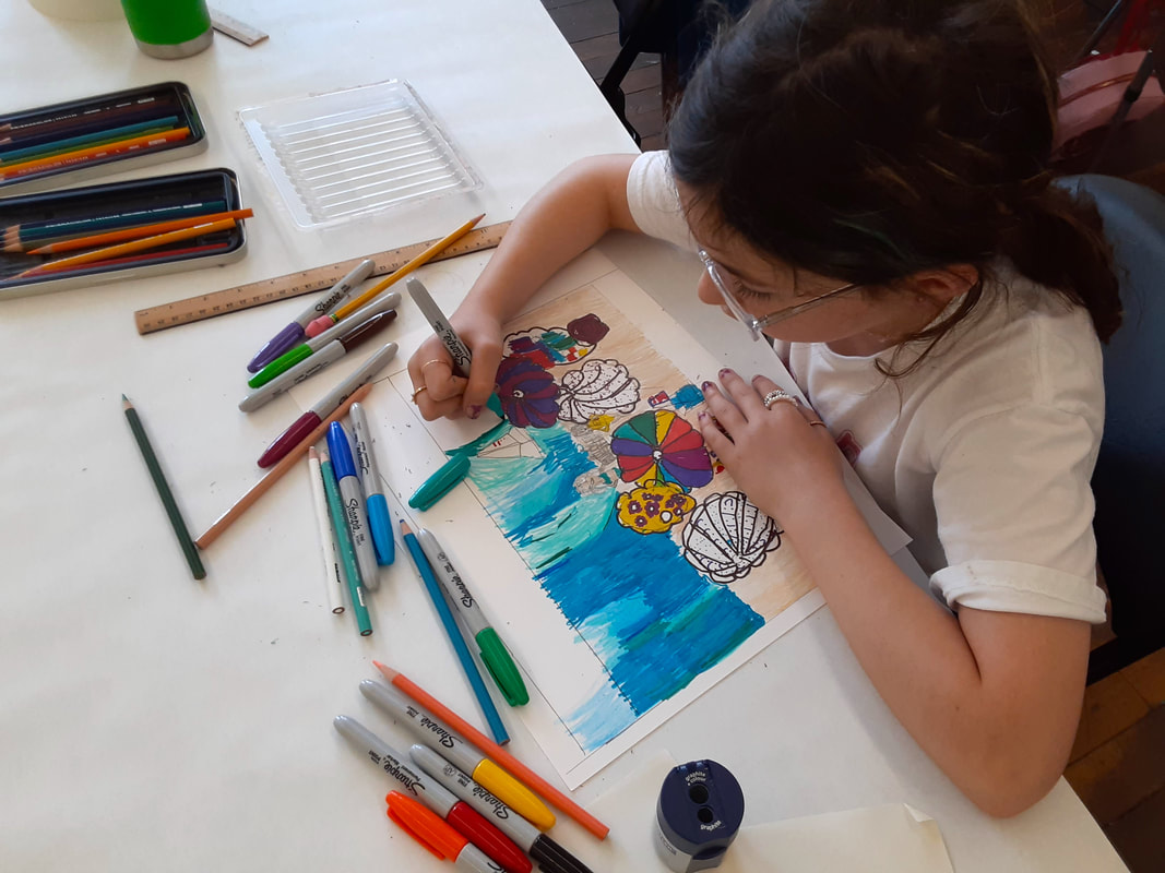 Child in art class creating a landscape drawing using colored pencils and markers.