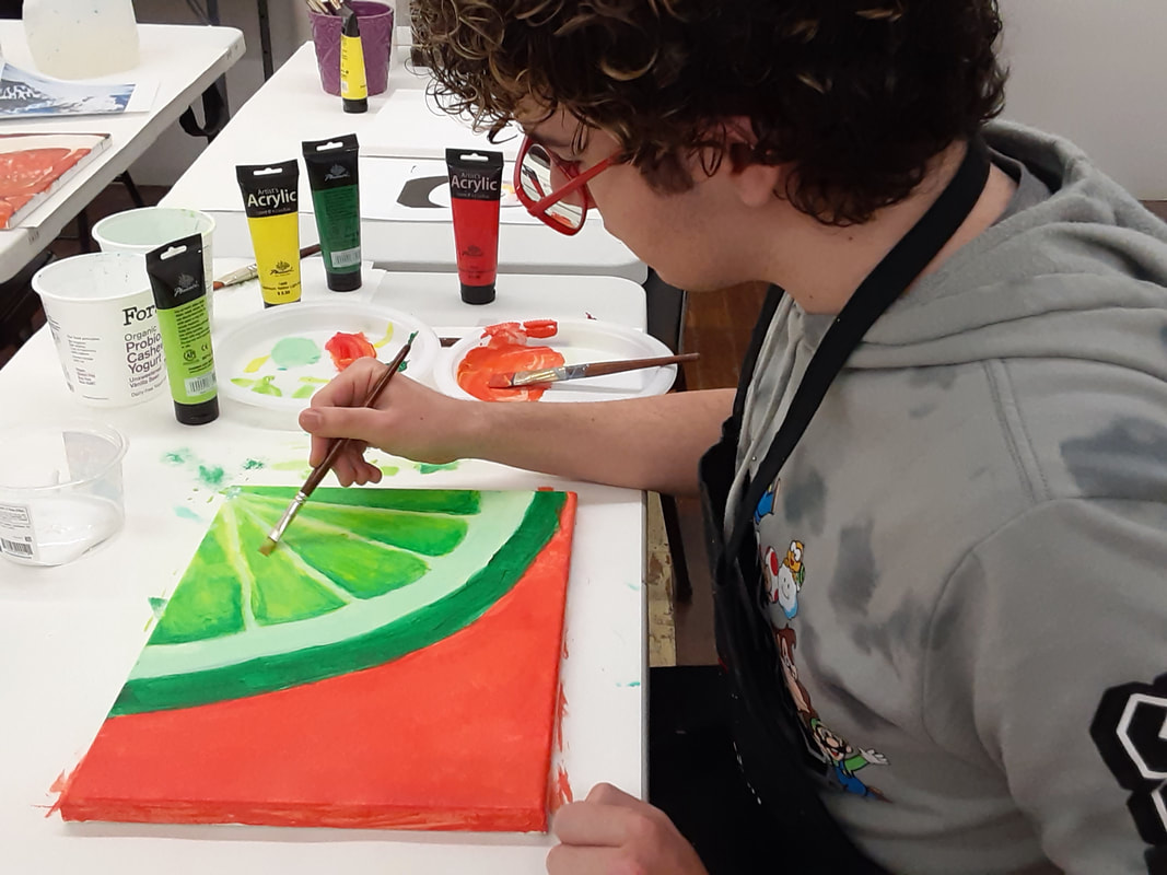 Teen painting a still-life using acrylic paints in a teen art class at an art school.
