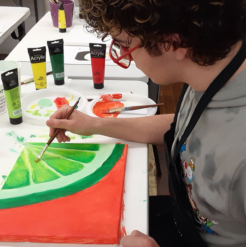 Teen painting a still-life using acrylic paints in a teen art class at an art school.